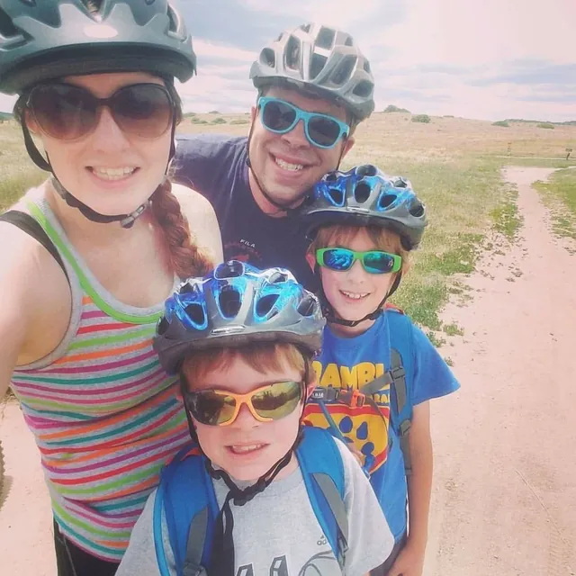 Shauna, Brian, Noah and Elijah smiling in bike helmets on a family bike ride