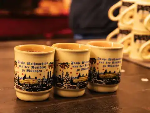 Row of decorated ceramic Glühwein mugs on a stall counter at Munich's Christmas market