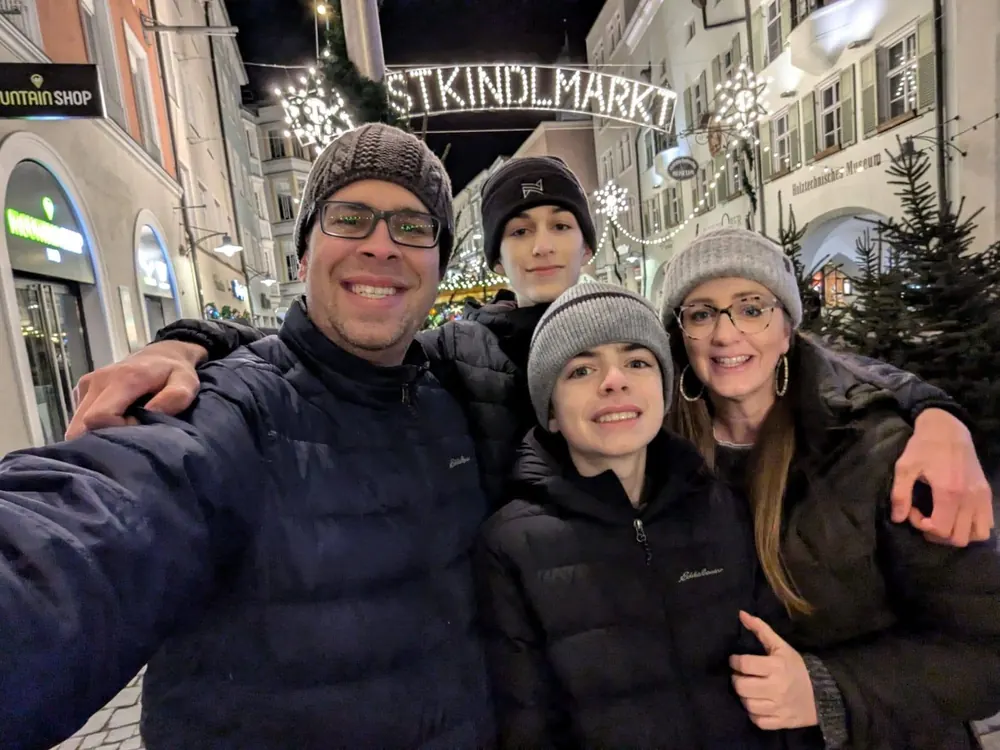 Brian, Noah, Elijah and Shauna smiling under the lit Christkindlmarkt sign at the Rosenheim Christmas market