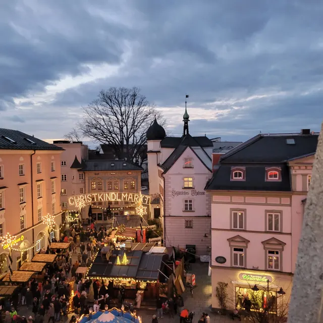 The Rosenheim Christkindlmarkt seen from above, with lit stalls and pastel old-town houses at dusk