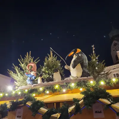 A penguin figure and little Christmas trees on a stall roof at the Rosenheim Christmas market