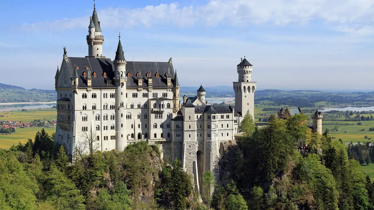 El castillo de Neuschwanstein sobre su cresta rocosa encima del bosque, visto desde el puente Marienbrücke