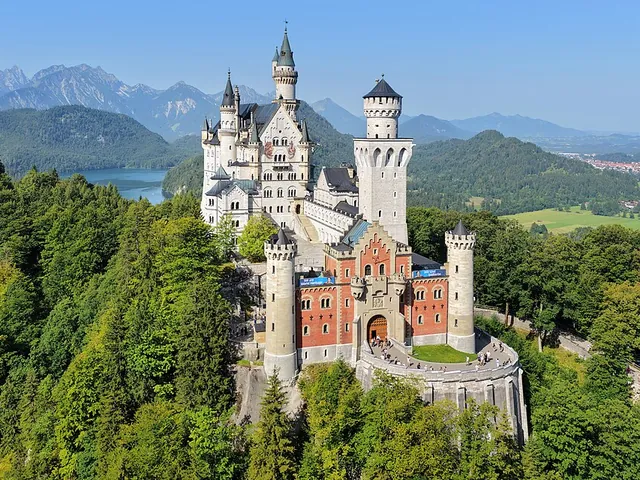 El castillo de Neuschwanstein con sus torres blancas sobre el bosque verde y las estribaciones de los Alpes