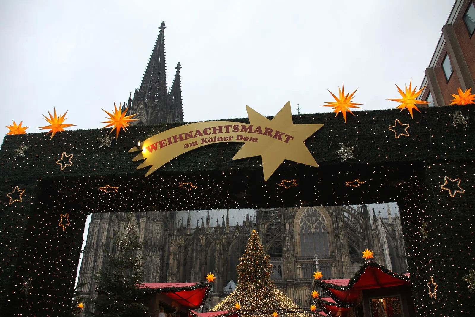 De met sterren versierde toegangspoort van de kerstmarkt bij de Dom van Keulen, met een torenspits van de Dom erachter