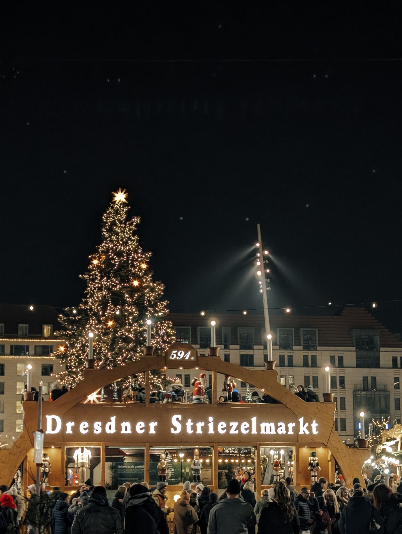 Dresdner Striezelmarkt entrance sign and a lit Christmas tree at night