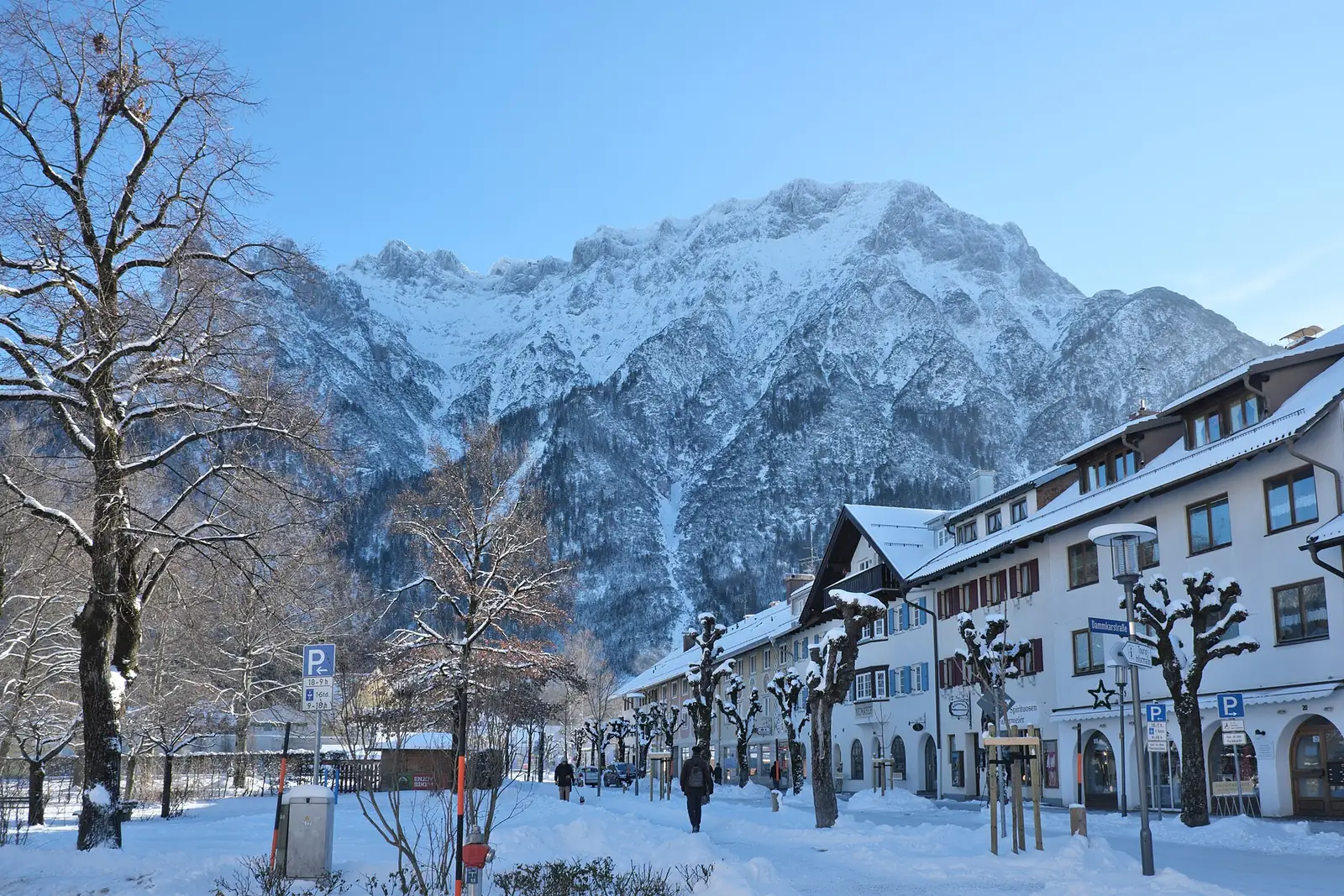 Verschneite Bahnhofstraße in Mittenwald, hinter den Häusern die tief verschneiten Berge