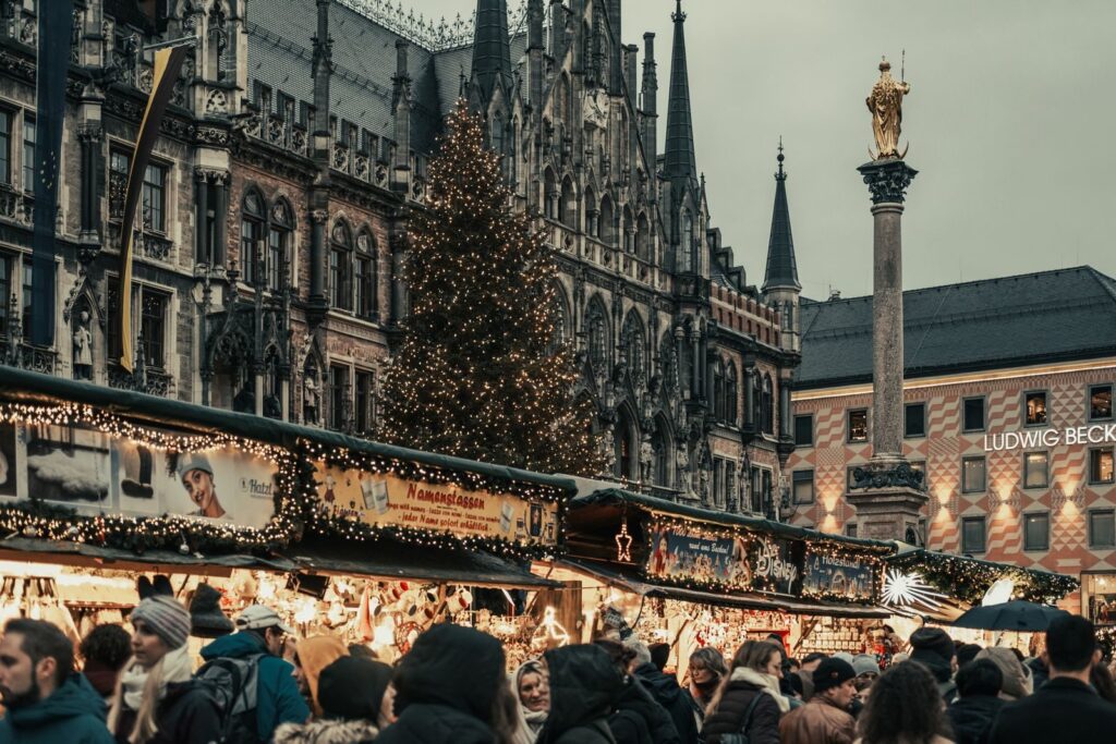 Christmas market stalls and a tall decorated tree in front of Munich's New Town Hall on Marienplatz.