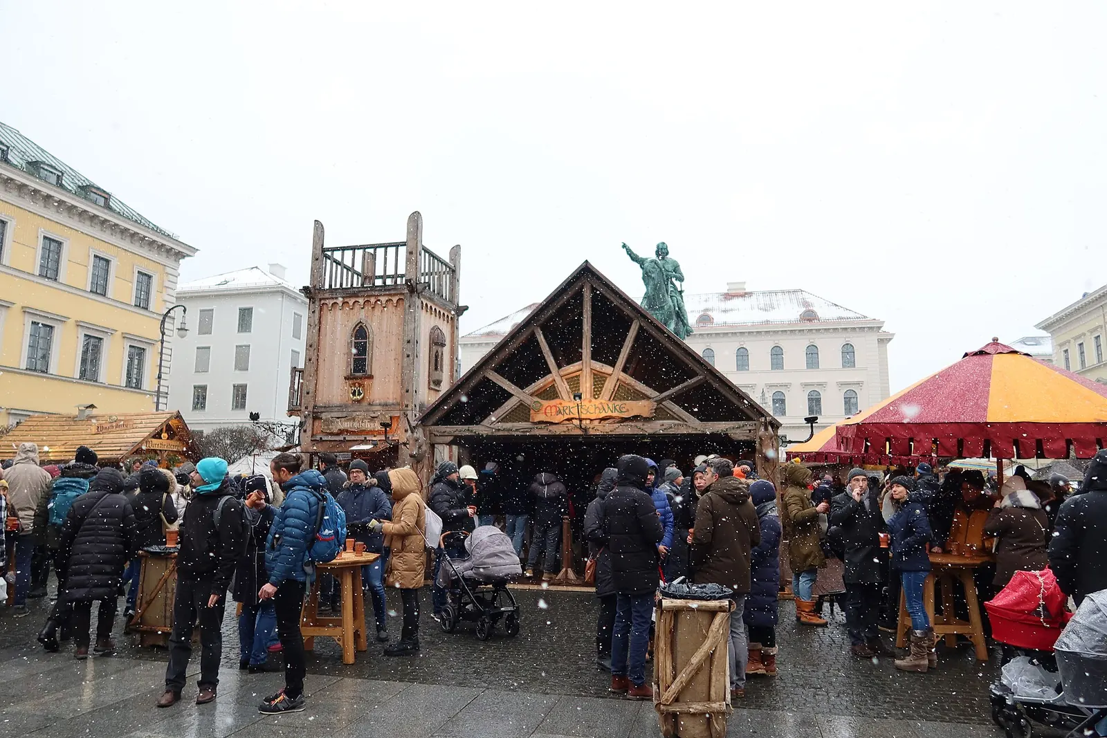 Besucher an der hölzernen Marktschänke des Mittelalterlichen Weihnachtsmarkts am Münchner Wittelsbacherplatz