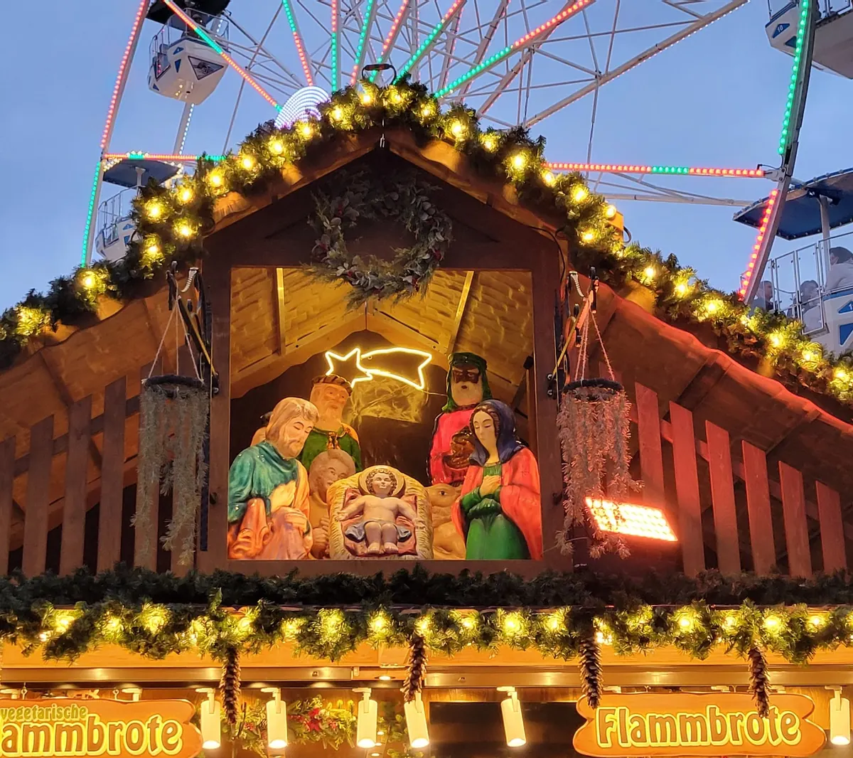 Nativity scene on the roof of a Flammkuchen stall at the Rosenheim Christmas market, with the Ferris wheel behind